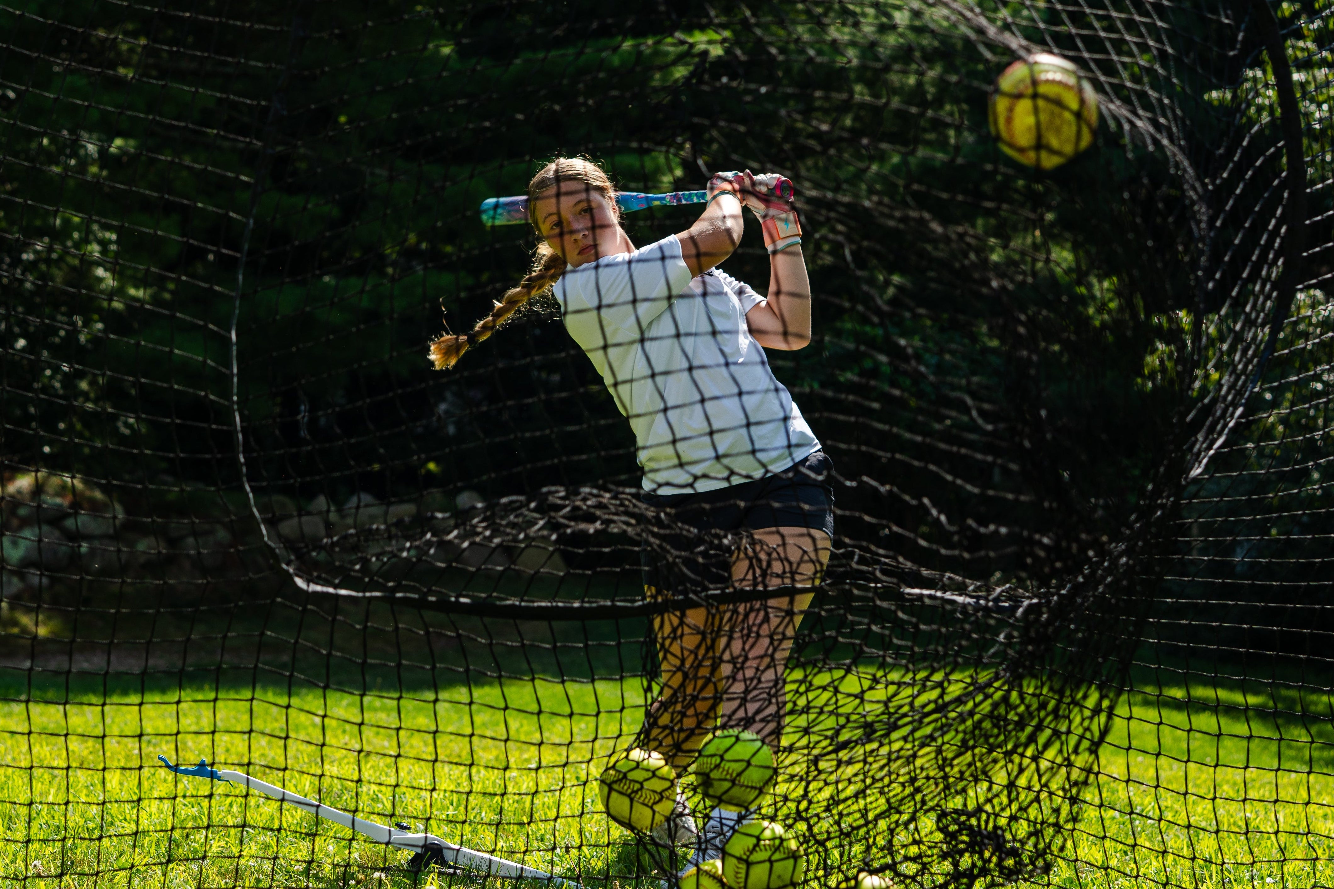 female hitting softballs into net